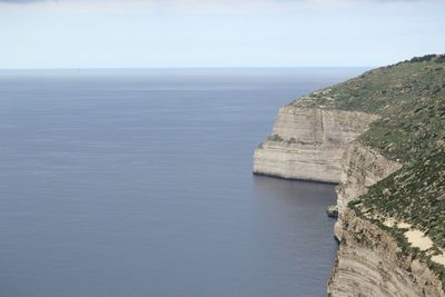 Scenic view of sea by cliff against sky