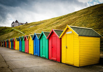 Colorful beach huts in row by hill