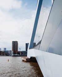 Modern buildings by river against sky in city