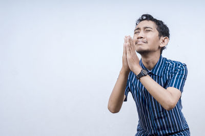 Young man looking away against white background