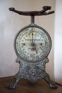 Close-up of clock on table against wall