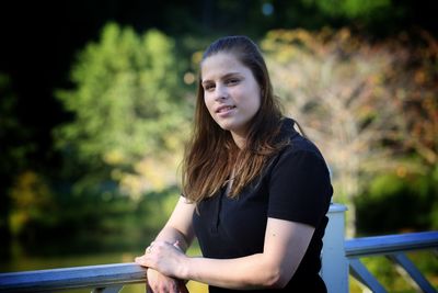 Portrait of young woman standing against trees