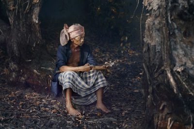 Man sitting on tree trunk in forest