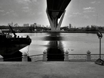 Bridge over river against cloudy sky
