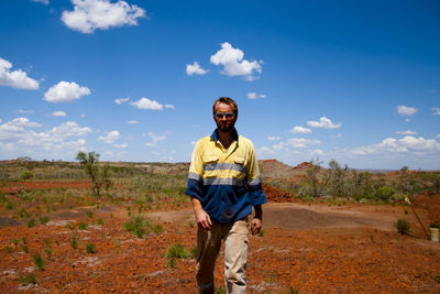 Young man standing on landscape against sky