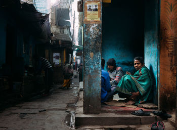 People sitting on street against buildings in city