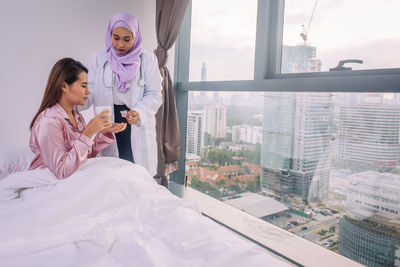 Woman using mobile phone at window