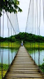 Rear view of man on footbridge against sky