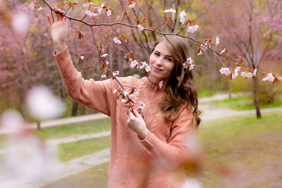 Pretty woman standing under pink blossom branch sakura