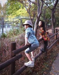 Rear view of mother and daughter on tree in park