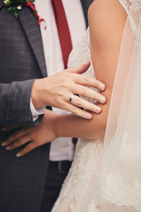 Midsection of bride and bridegroom holding hands