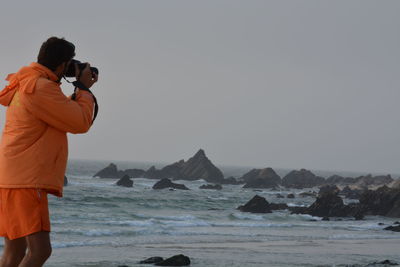 Rear view of woman holding sea against clear sky