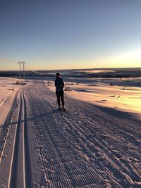 Rear view of man walking on snow covered land