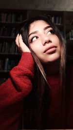 Thoughtful young woman looking up at home