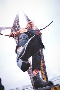 Low angle view of man holding umbrella against sky