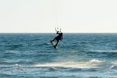 Man surfing on sea against clear sky