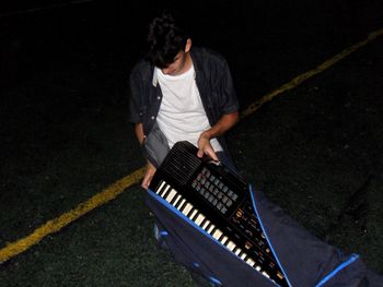 High angle view of man putting piano keyboard in cover on street at night