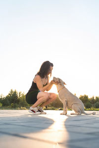 Woman with dog against clear sky