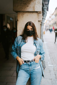 Portrait of man wearing mask standing against built structure