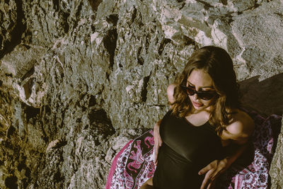 High angle view of woman wearing sunglasses sitting on rock formation