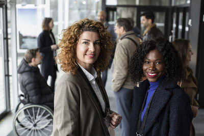 Portrait of smiling female business delegates standing in lobby of conference center