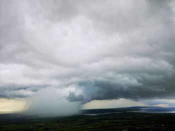 Storm clouds over land with cloudburst in distance.