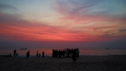 People on beach against sky during sunset