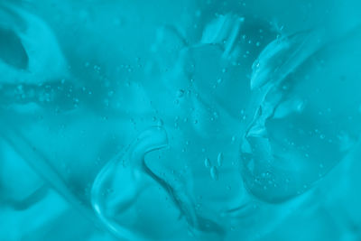 The texture of transparent antiseptic gel with air bubbles on blue background. skin moisturizing