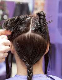 Close-up of hairdresser making hairstyle for customer at salon