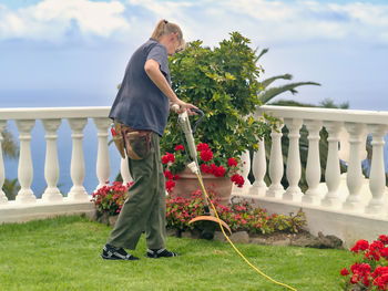 Full length of woman cutting grass in garden