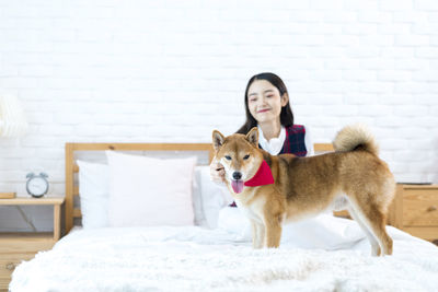 Woman with dog sitting on bed