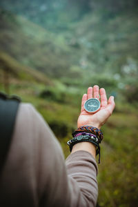 Midsection of woman holding navigational compass on mountain