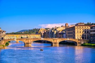 Arch bridge over river against blue sky