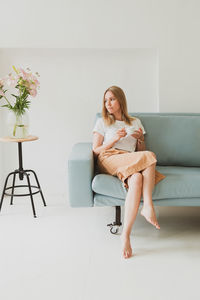 Full length of woman sitting on chair at home