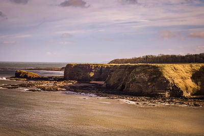 Rock formations on beach against sky