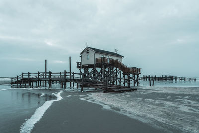 Pier on beach against sky