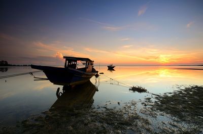 Boat moored in sea against sky during sunset