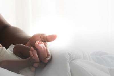 Low section of child relaxing on bed