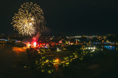 Firework display over river against sky in city at night