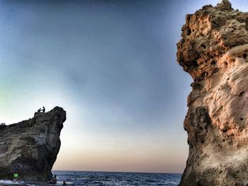 Rock formations by sea against sky