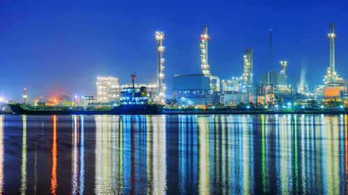 Illuminated factory against blue sky at night oil refinery
