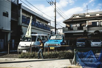 Man standing by cars against sky