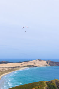 Paragliding over the sand dune and blue ocean