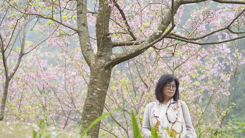 Portrait of smiling woman standing by tree