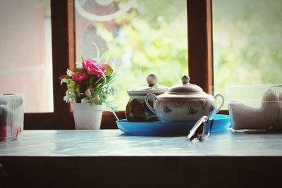 Flower vase on table against window