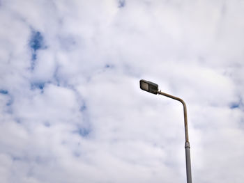 Low angle view of street lighting post against cloudy sky