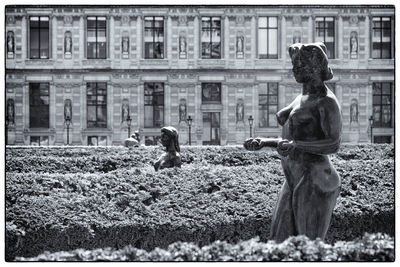 Statue by plants at park against building