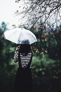 Woman standing on wet umbrella during rainy season