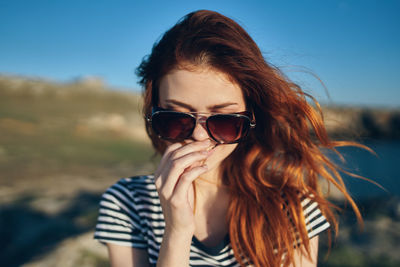 Portrait of young woman wearing sunglasses against sky