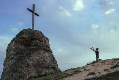 Low angle view of man standing on rock against sky